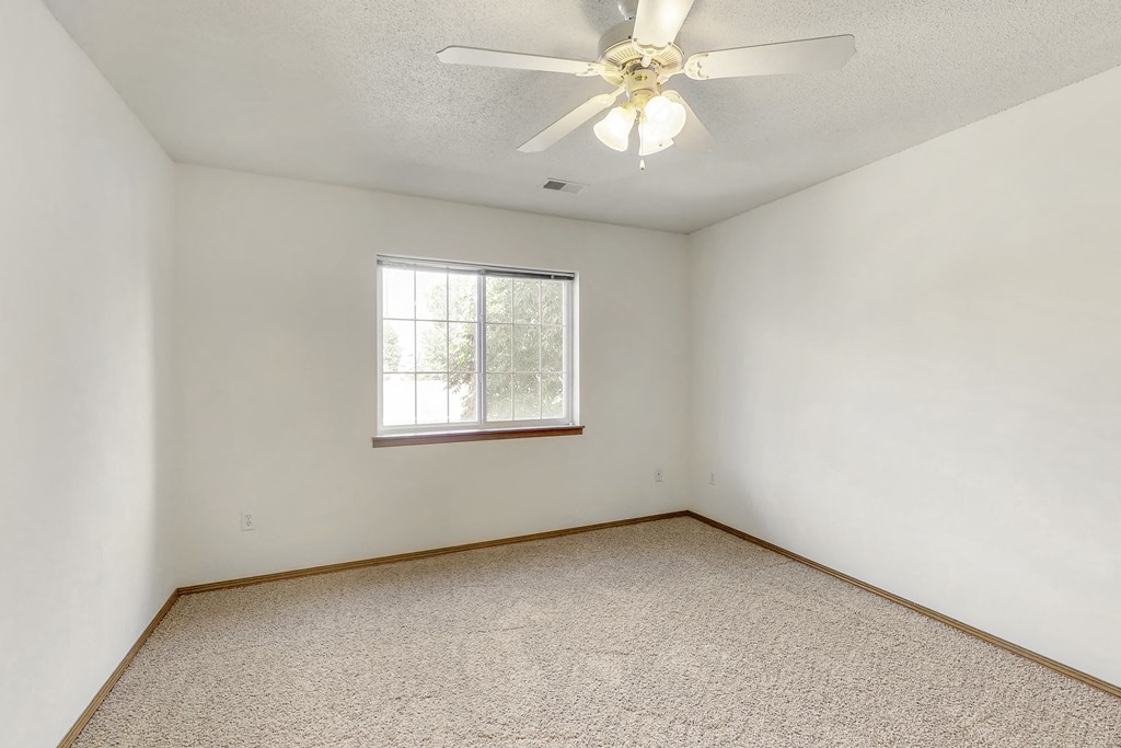 an empty room with a ceiling fan and a window