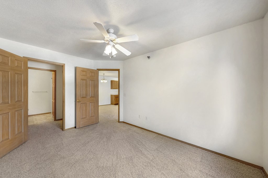 an empty living room with white walls and a ceiling fan