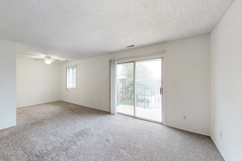 an empty living room with a sliding glass door to a patio