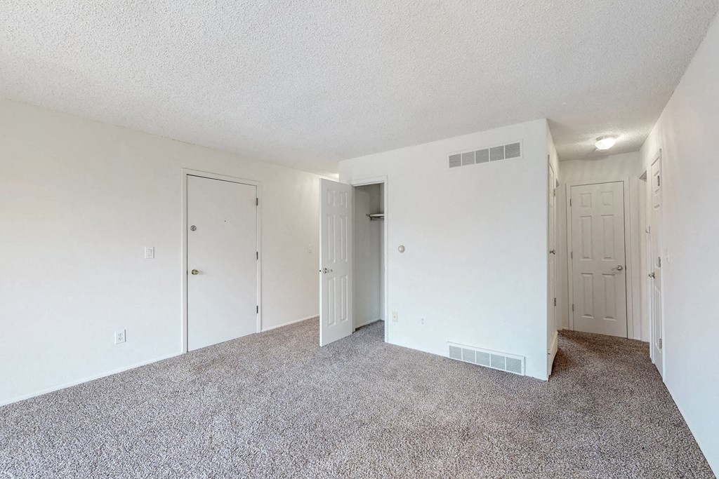 the spacious living room with white walls and carpeting