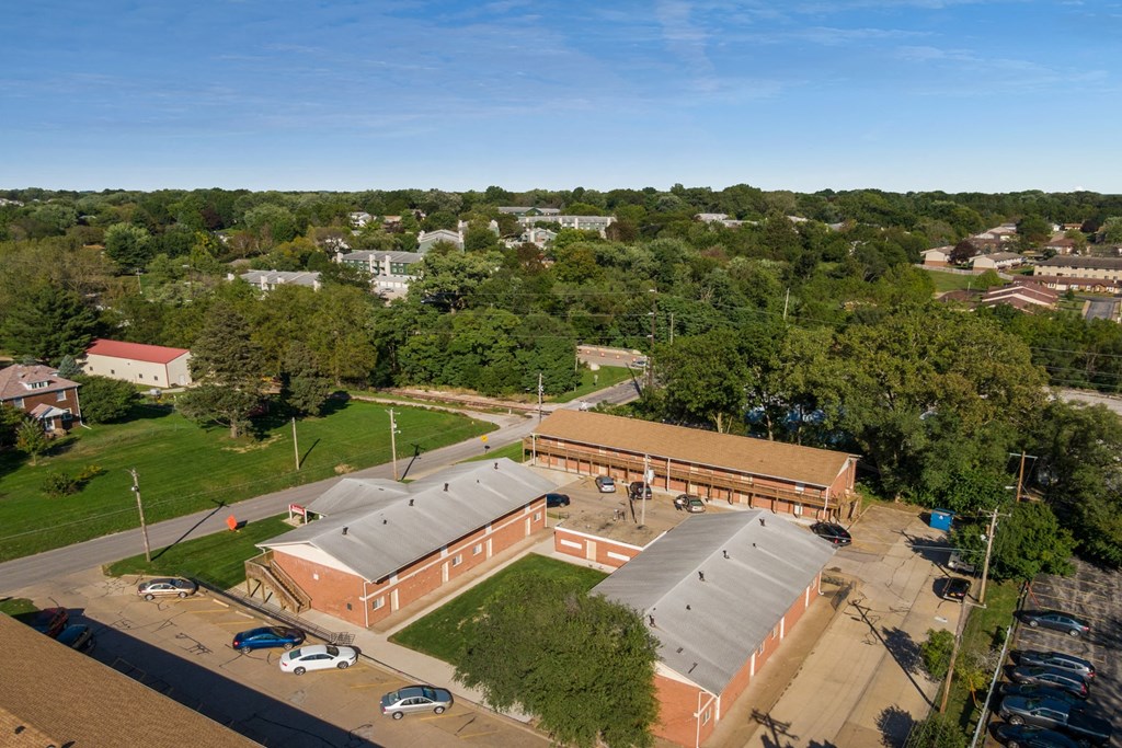 an aerial view of a building with a parking lot and trees