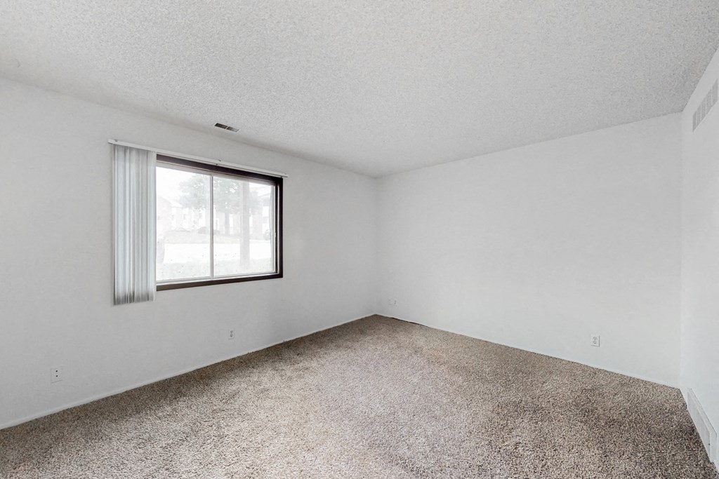 an empty room with a window and a carpeted floor