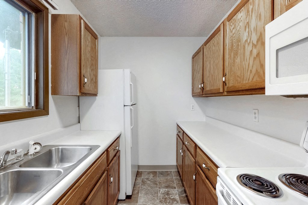 a kitchen with wooden cabinets and a white stove and refrigerator