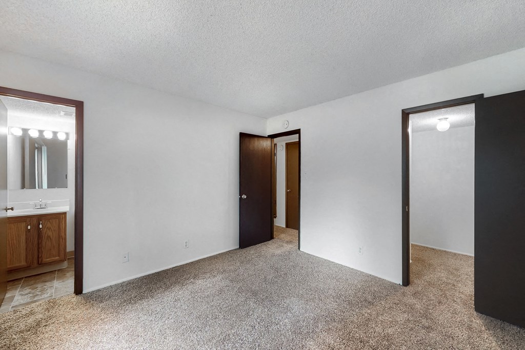 an empty living room with white walls and a door to a bathroom