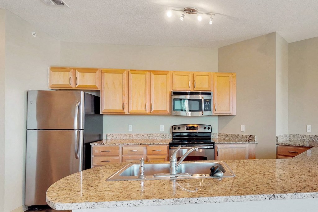 a kitchen with a granite counter top and a stainless steel refrigerator
