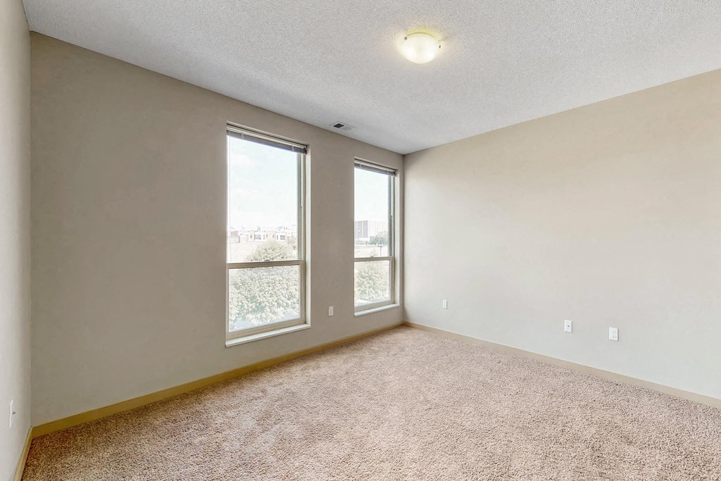 an empty living room with large windows and carpeting