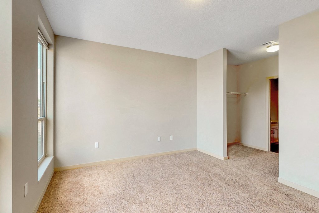 an empty living room with a large window and carpet