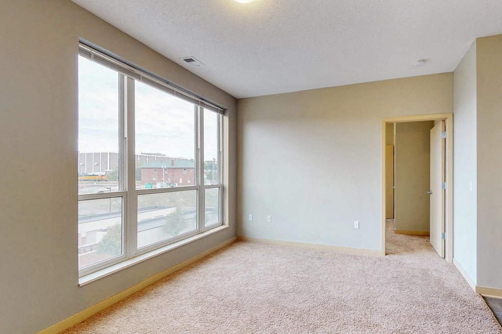 an empty living room with large windows and a door to a hallway