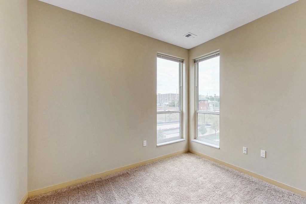 an empty living room with two windows and a carpeted floor