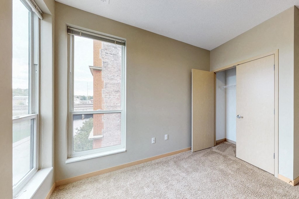 a bedroom with a large window and a door to a closet