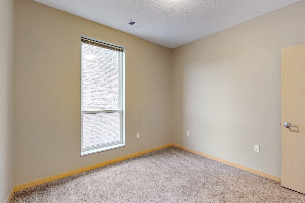 an empty room with a large window and carpet