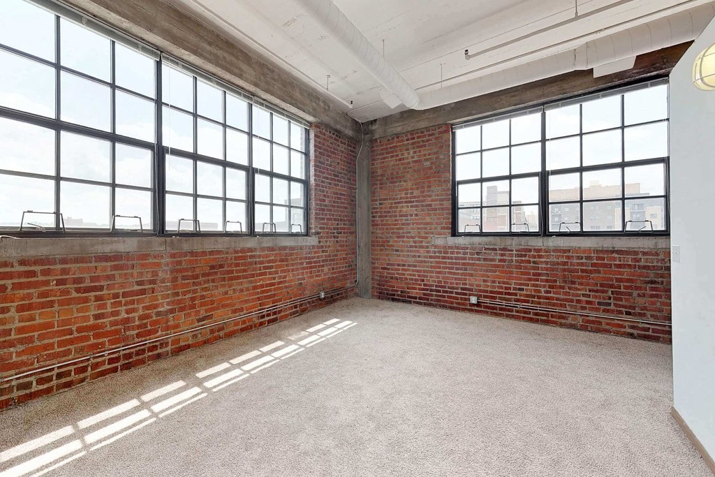 an empty room with a brick wall and large windows