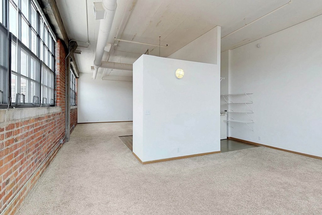an empty room with a brick wall and a white partition in the middle
