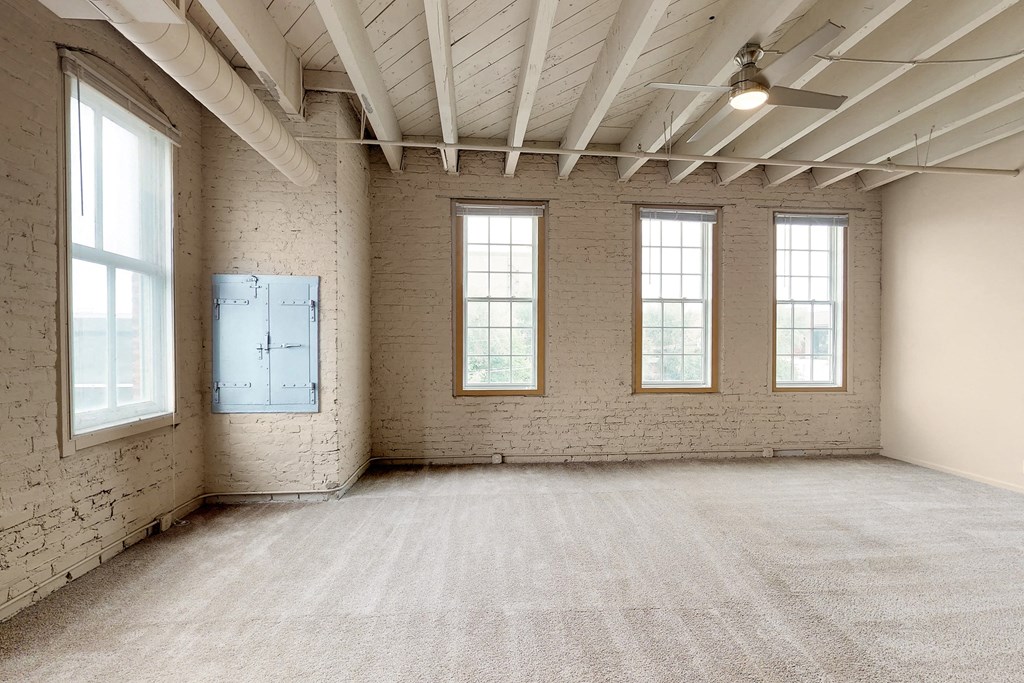 an empty room with three windows and a carpeted floor