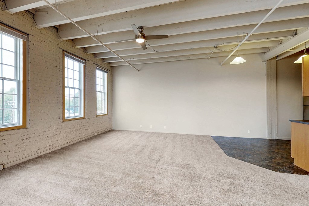 an empty room with a rug and a ceiling fan