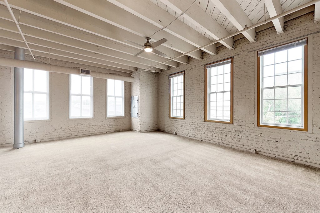 an empty room with three windows and a carpeted floor
