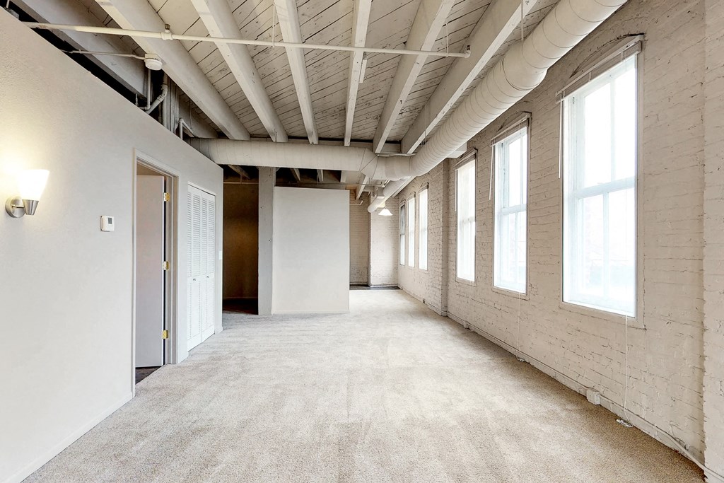 the interior of an empty room with white walls and a concrete floor and windows