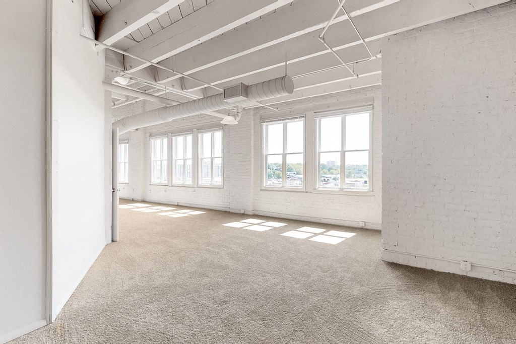 an empty room with three windows and a concrete floor