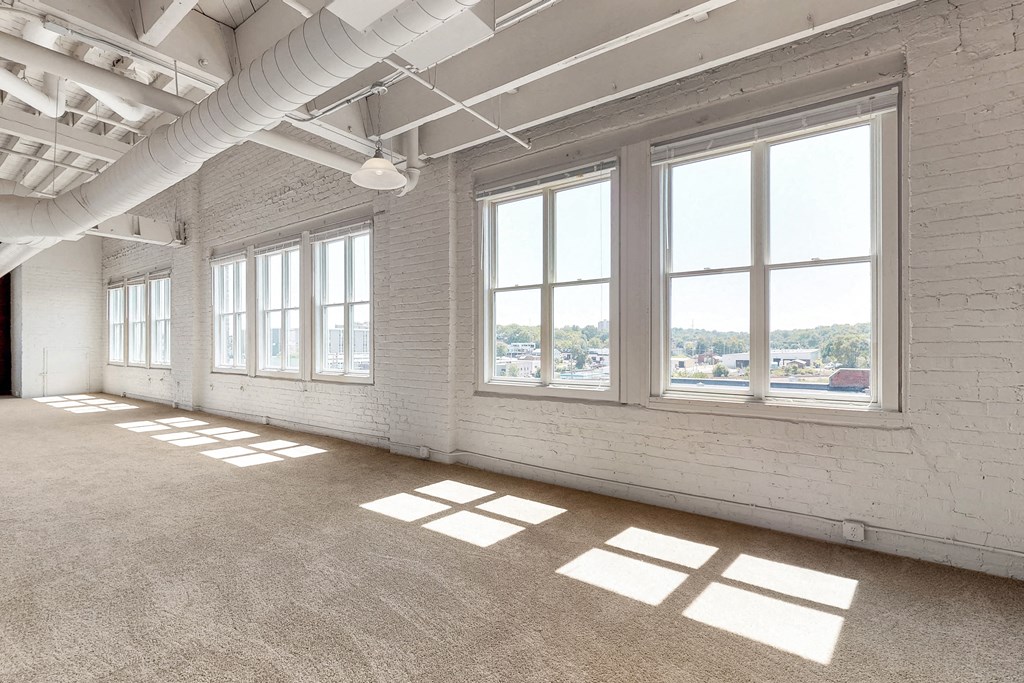 an empty room with large windows and a carpeted floor