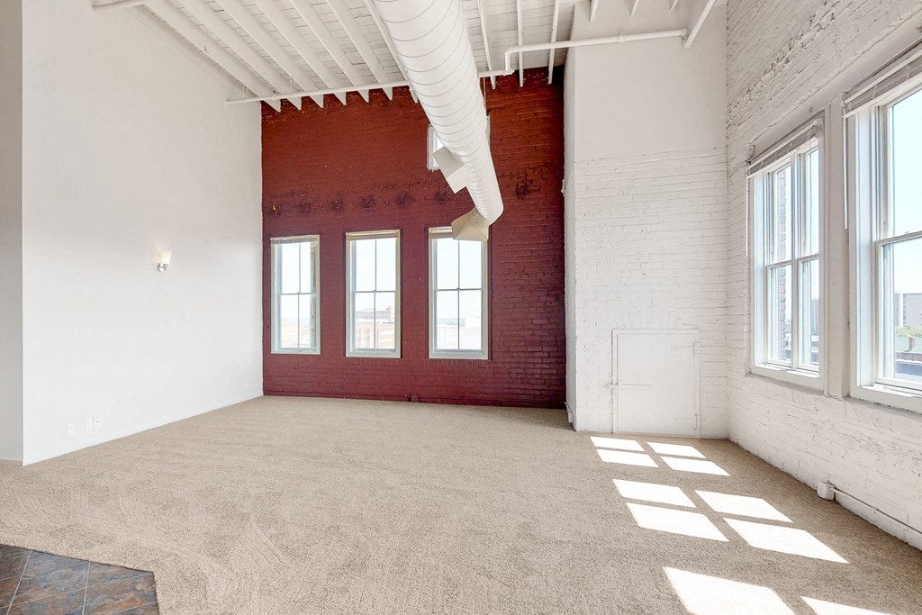 an empty room with windows and a red brick wall
