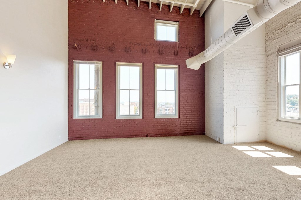 an empty room with a brick wall and three windows