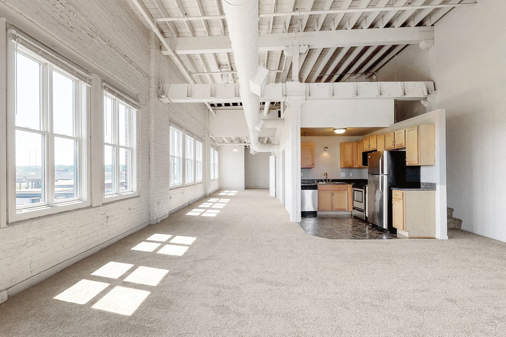 the interior of an empty apartment with a kitchen and large windows