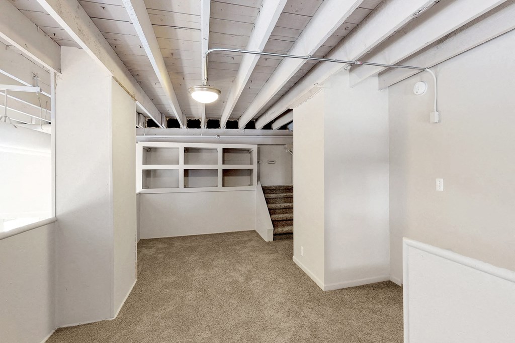 a renovated basement with white walls and a closet with white shelves