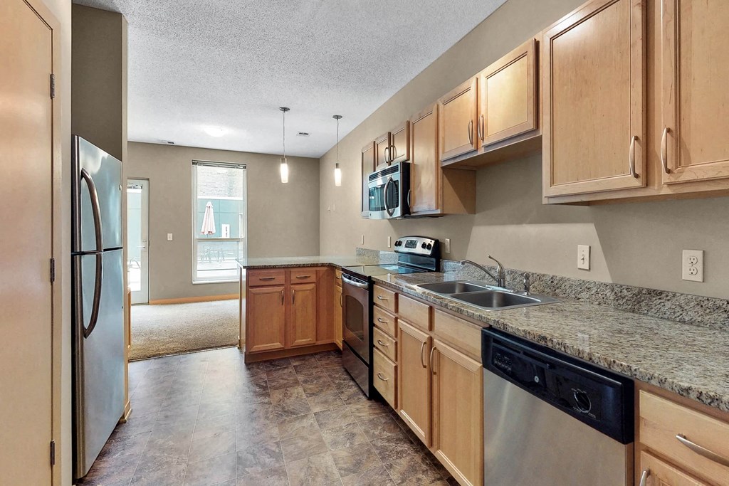 an empty kitchen with wooden cabinets and stainless steel appliances