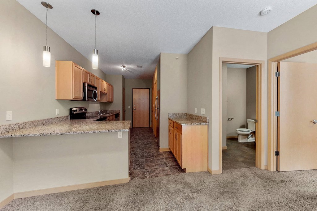 a kitchen with a counter top and a long hallway with a toilet and a sink