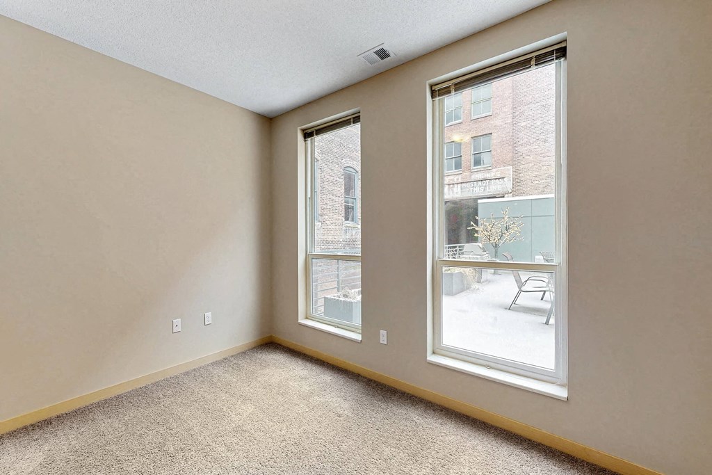 an empty bedroom with a large window and carpeted flooring