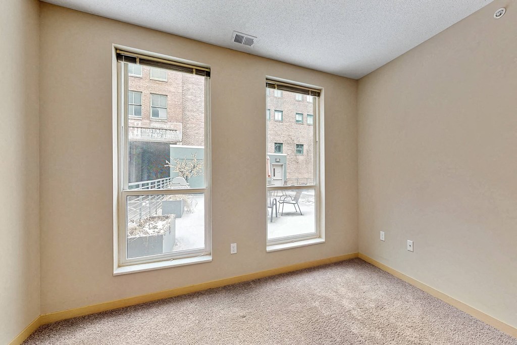 an empty room with two windows and a carpeted floor