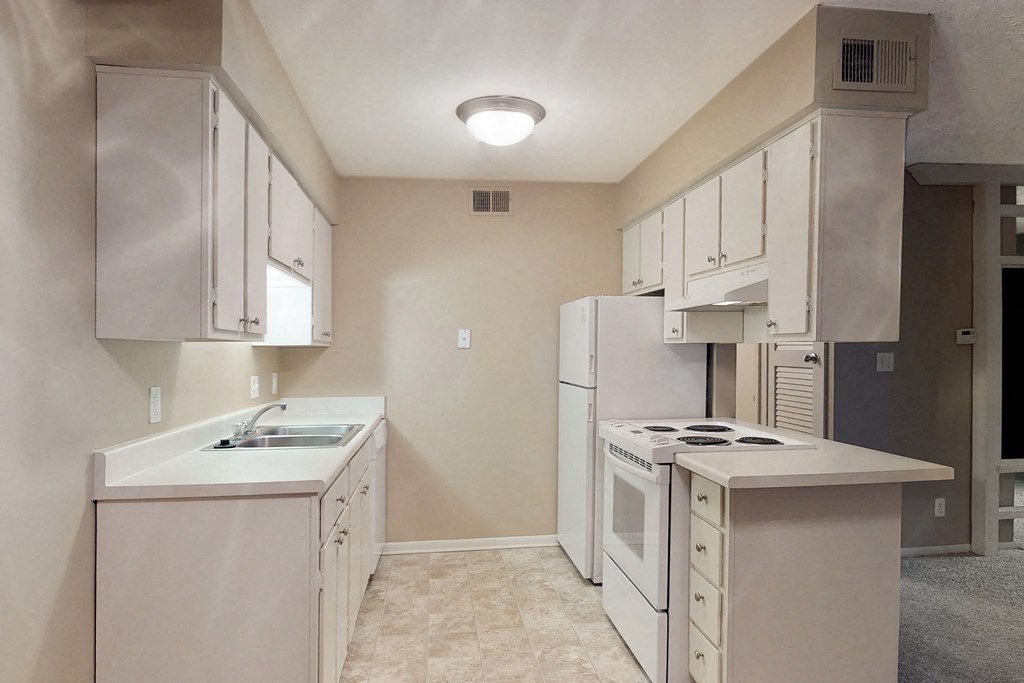 an empty kitchen with white appliances and white cabinets