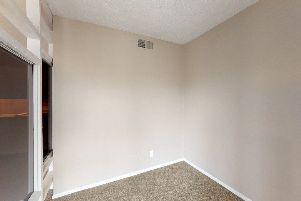 an empty room with white walls and a sliding glass door