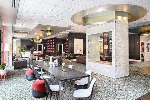 A modern dining area with a long table surrounded by chairs at Sophia Square Apartments, Carmel, Indiana