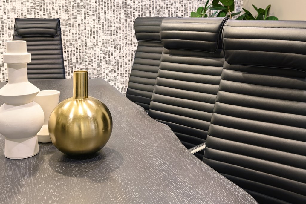 a row of black leather chairs and a table with a gold vase