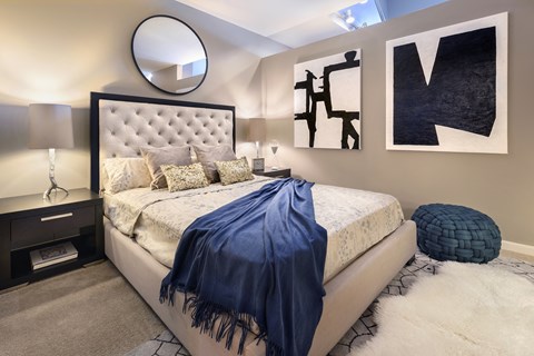 A bedroom with a large bed and a blue blanket at Sophia Square Apartments, Carmel, IN