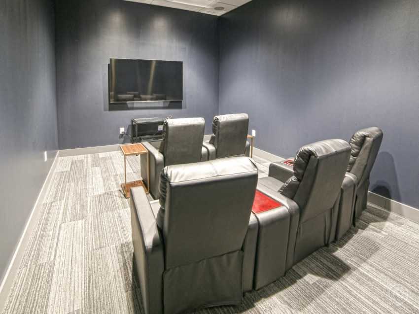 a theater room with leather chairs and a television