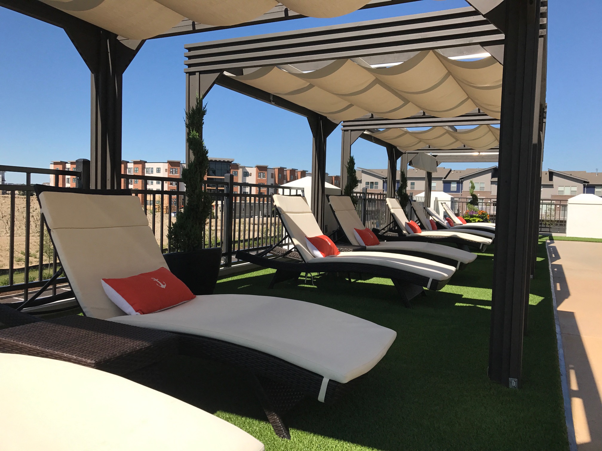 a row of lounge chairs under a canopy on a rooftop