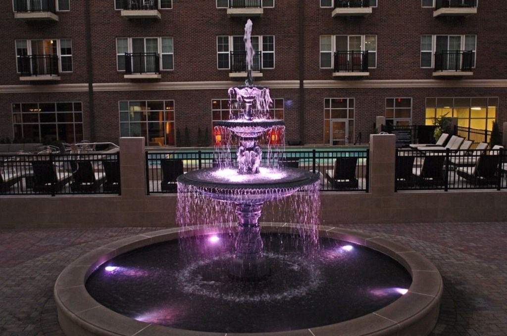 the fountain is lit up at night with purple lights