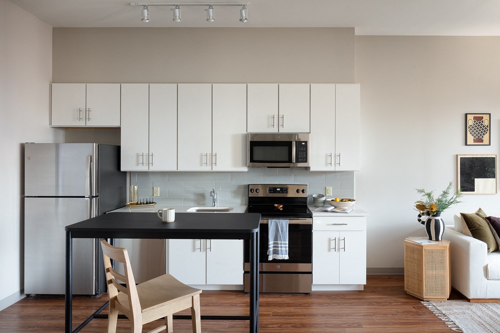 a kitchen with white cabinets and a black counter top