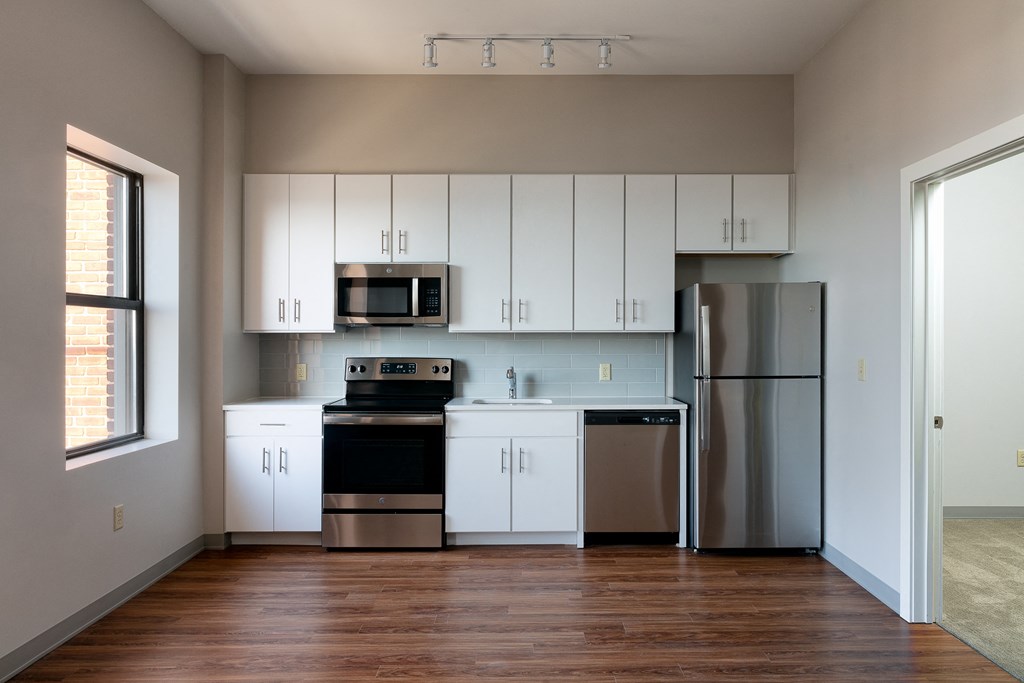 an empty kitchen with white cabinets and stainless steel appliances