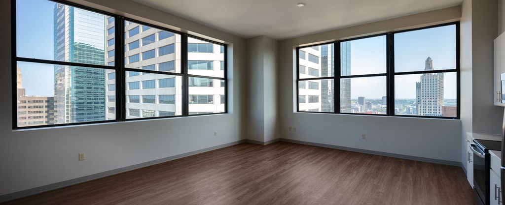 an empty living room with large windows and wood floors