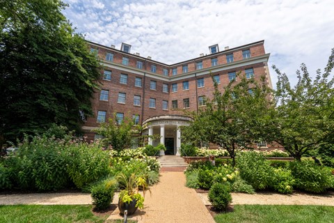 A large red brick building with a white entrance and a garden in front.