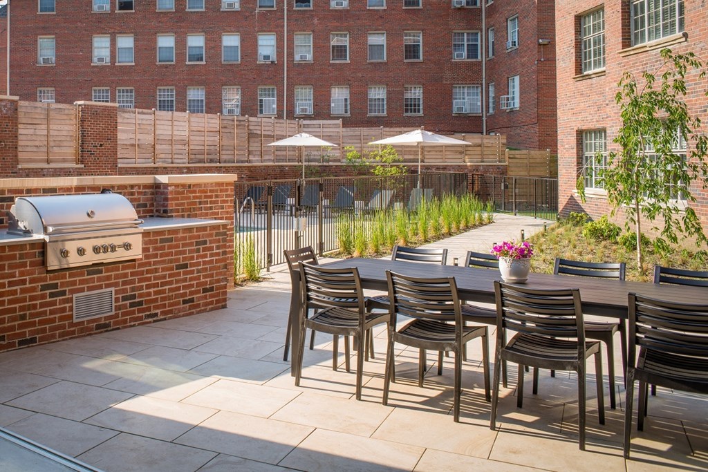 a patio with a barbecue grill and a table with chairs