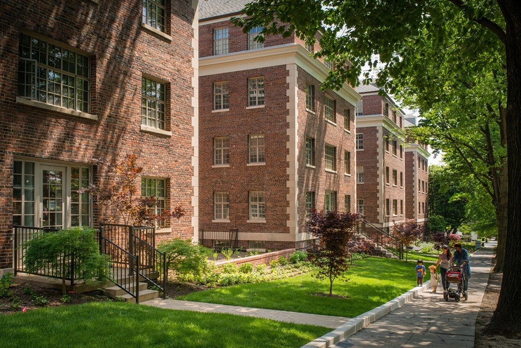 people walking down a sidewalk in front of a brick building