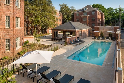 A pool area with a white umbrella and black lounge chairs.