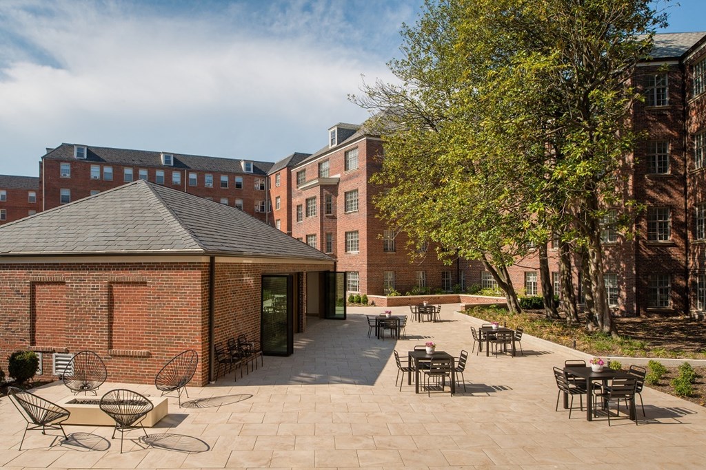 a courtyard with tables and chairs in front of a brick building