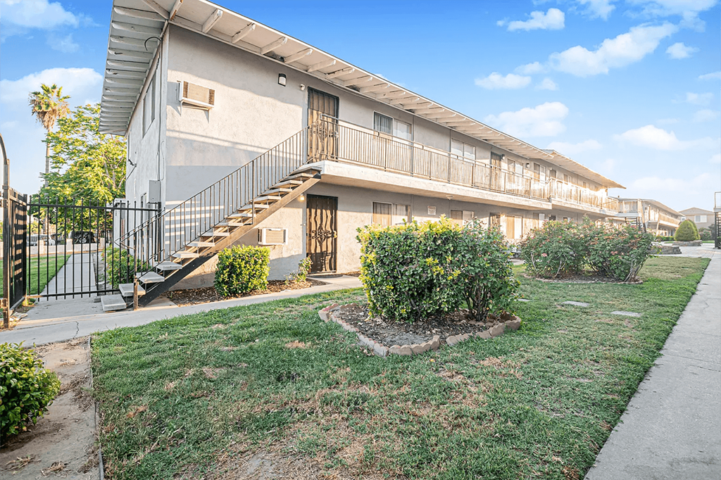 A building with a balcony and a small garden in front.