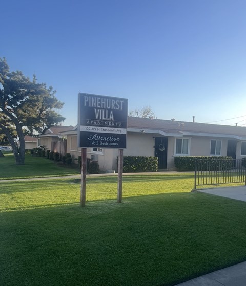 A sign for Pinehurst Villa Apartments stands in front of a building.
