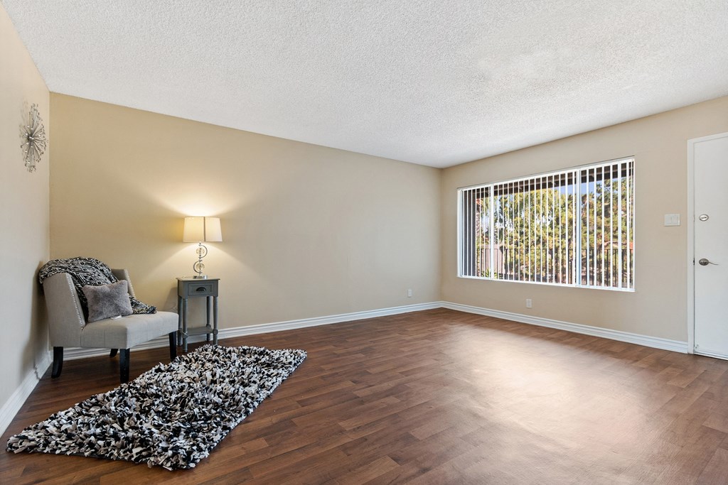 an empty living room with a chair and a rug at Terramonte Apartment Homes, Pomona, CA